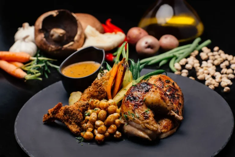 Poulet rôti, pois chiches et carottes sur une assiette noire