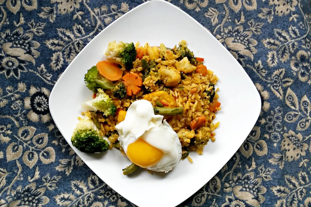 Riz sauté aux légumes et œuf poché dans une assiette