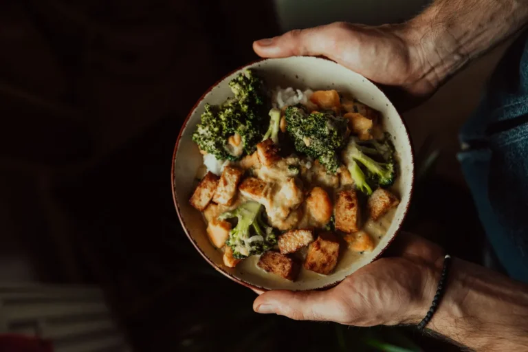Bol de tofu doré et de brocoli tenu à deux mains