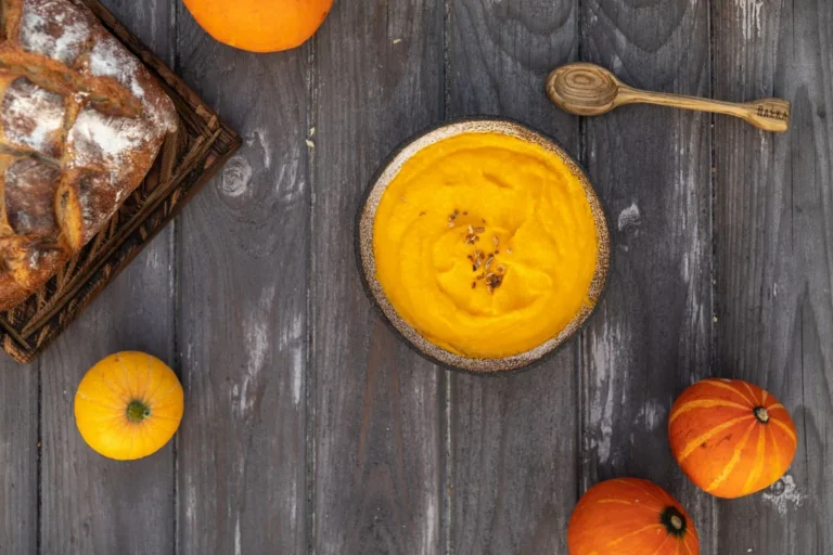 Velouté orange de courge, petites courges sur une table en bois